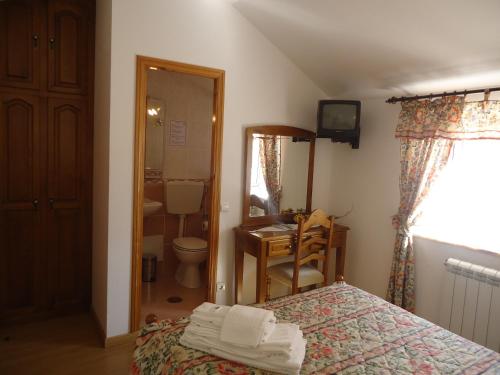 a bedroom with a bed and a bathroom with a toilet at Hotel Aviz in Figueira da Foz