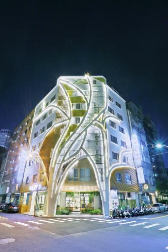 a large white building with a spiral facade at night at Green Hotel - West District in Taichung