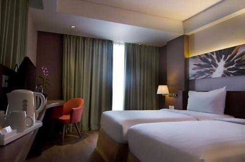 um quarto de hotel com duas camas e uma secretária em Soll Marina Hotel Serpong em Serpong