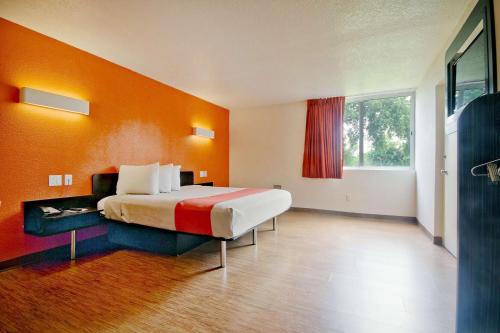 ein Schlafzimmer mit einem großen Bett und einer orangefarbenen Wand in der Unterkunft Motel 6-Miami, FL in Miami