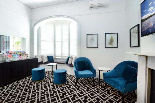 a waiting room with blue chairs and a fireplace at High Cross Randwick by Sydney Lodges in Sydney