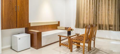 a small room with a bed and a table and a chair at Pushpak Resort in Shirdi