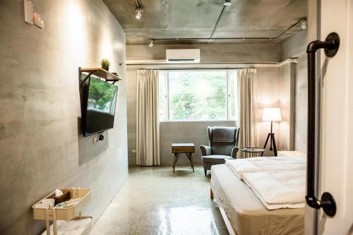 um quarto com uma cama, uma televisão e uma cadeira em Genuinn em Taitung City