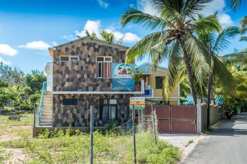 a building with a palm tree in front of it at Merlin Guest House in Rodrigues Island