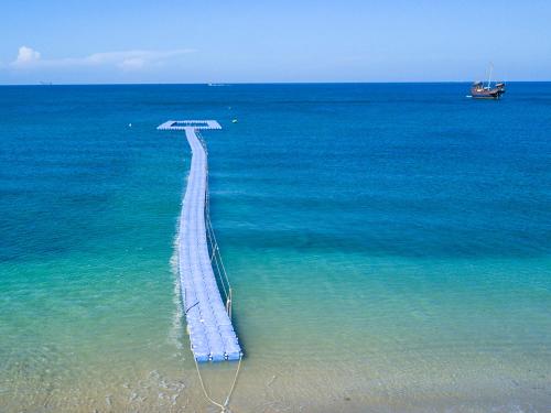a pathway in the ocean with a boat in the water at Rawi Warin Resort And Spa - SHA Extra Plus in Ko Lanta