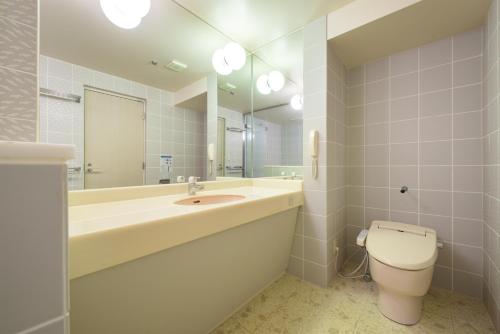 een badkamer met een wastafel, een toilet en een spiegel bij Aomori Winery Hotel in Ōwani