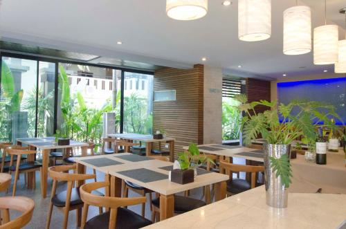a restaurant with wooden tables and chairs and plants at Blue Tara Hotel Krabi Ao Nang in Ao Nang Beach