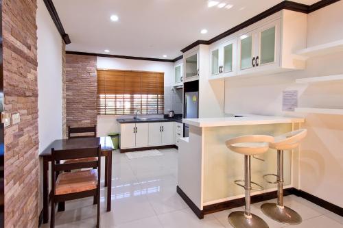 a kitchen with white cabinets and a bar with stools at V Condominium Samui in Bophut