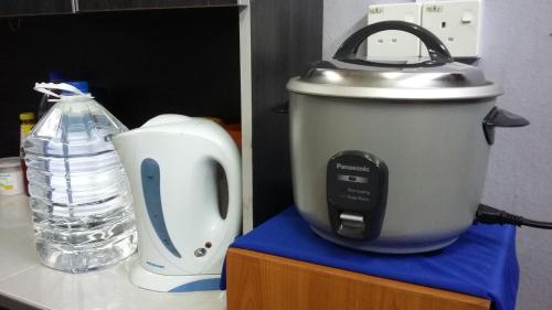a slow cooker on a counter next to a bottle of water at Kayangan Homestay Perlis for Mslim Only in Kangar