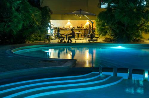 a swimming pool at night with people sitting at a table at Abbaechelu in Santa Margherita di Pula