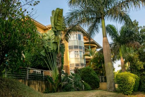 a yellow house with palm trees in front of it at Enkombe Place in Kampala