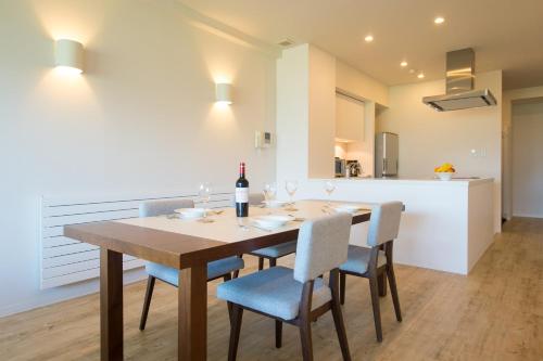 a dining room table with chairs and a bottle of wine at Niseko Landmark View in Kutchan