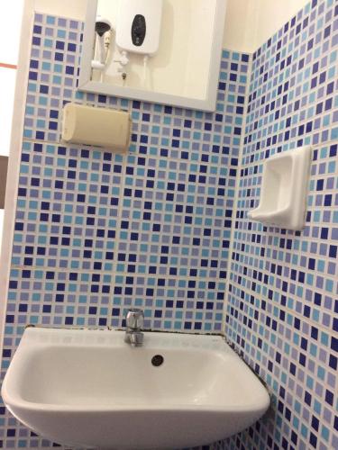 a blue tiled bathroom with a white sink at InnBox Bed & Bath in Panglao Island