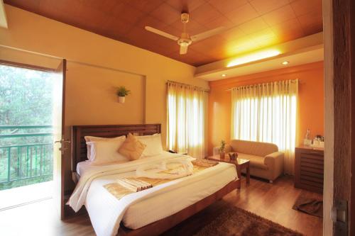 a bedroom with a bed and a chair and a window at Grand Plaza in Munnar