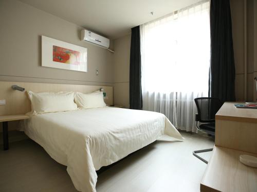 a bedroom with a white bed and a large window at Jinjiang Inn Lvliang Changzhi Road in Luliang