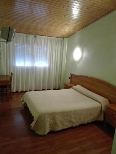 a bedroom with a bed and a window with white curtains at Hotel Restaurant Casa Miquel in Alcarraz