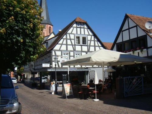 ein weißes und schwarzes Gebäude mit einem Tisch und einem Regenschirm in der Unterkunft Malerwinkel & Tuchereck in Michelstadt