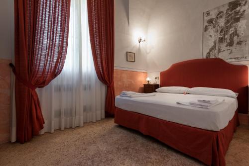 una camera da letto con un letto con testiera rossa e una finestra di Palazzo Laura a Morciano di Leuca