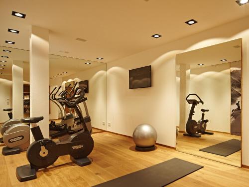 a gym with treadmills elliptical machines and mirrors at Chalet-F in Ofterschwang