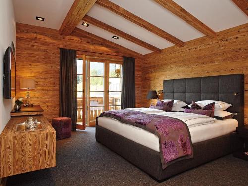 - une chambre avec un grand lit et un mur en bois dans l'établissement Chalet-F, à Ofterschwang