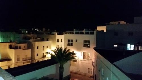 a view of buildings at night with a palm tree at Apartamento Mayte in Conil de la Frontera