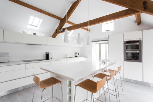 a kitchen with white cabinets and a white table and chairs at Owl Barn at Penygaer Great views of Brecon Beacons in Llandovery