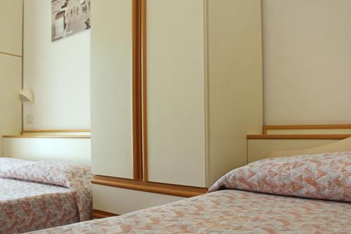 a bedroom with two beds and a closet at Hotel Silvia in Misano Adriatico