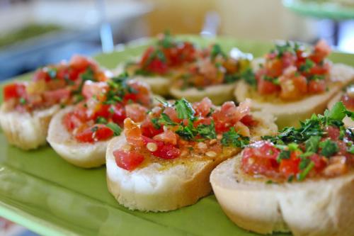 a green plate topped with small sandwiches with salsa at Hotel Touring in Misano Adriatico