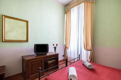 a bedroom with a bed with a tv and a window at Domus Sessoriana in Rome