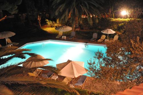 a large swimming pool with umbrellas and chairs and sidx sidx sidx at Niki Hotel Apartments in Ialyssos