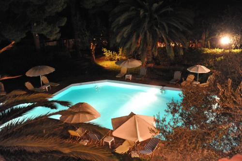 a swimming pool at night with umbrellas at Niki Hotel Apartments in Ialyssos