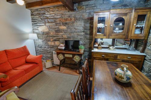 a living room with a red couch and a table at A Casoa II in Santa Eulalia de Oscos