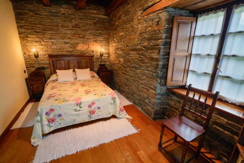 1 dormitorio con cama y pared de ladrillo en A Casoa II, en Santa Eulalia de Oscos