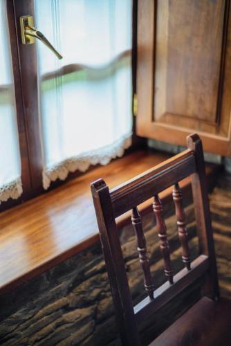 a wooden chair sitting in front of a door at A Casoa II in Santa Eulalia de Oscos