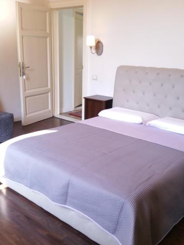 a bedroom with a large white bed and a door at B&B Villa Regina in Pisa
