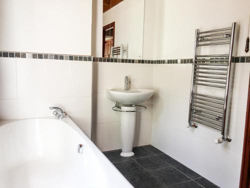 a white bathroom with a sink and a bath tub at Highwood Lodge in Scissett