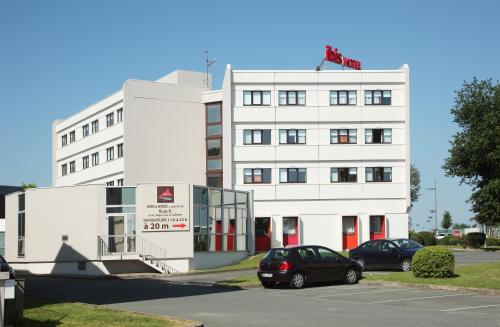 a white building with cars parked in a parking lot at ibis Poitiers Sud in Poitiers