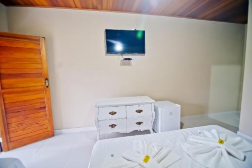a bedroom with a bed and a tv on a wall at Vila Noah Pousada in Paraty