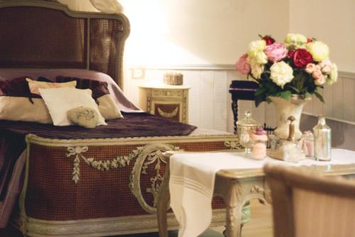 a room with a bed and a table with a vase of flowers at Le Bonheur à la Campagne in Lesmont