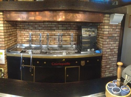 a grill in a kitchen with a brick wall at ibis Poitiers Sud in Poitiers