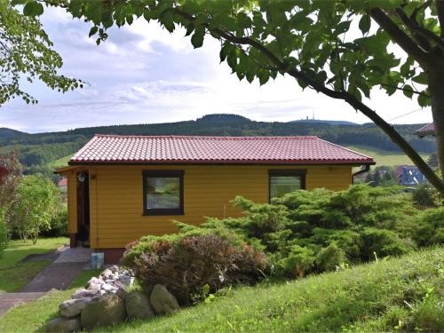 una casa amarilla con techo rojo en Holiday home with private garden, en Waltershausen