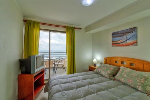 1 dormitorio con cama, TV y balcón en Departamento Mondaca Vista Mar, en Valparaíso
