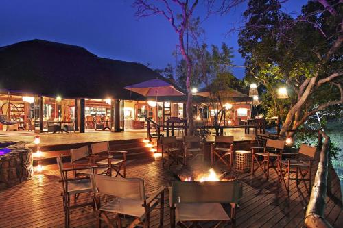a restaurant with tables and chairs on a deck at night at Ndlovu Safari Lodge in Welgevonden Game Reserve