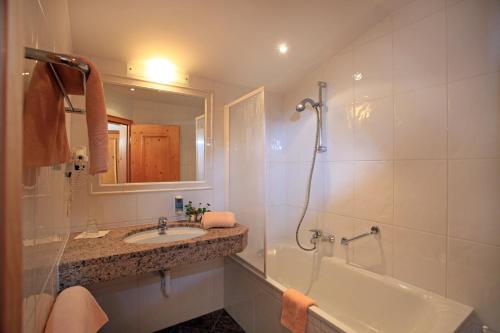 a bathroom with a tub and a sink and a shower at Appartementhaus Seehof in Kirchberg in Tirol