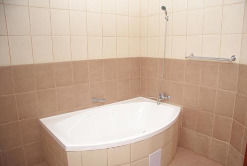 een bad in een betegelde badkamer met een douche bij Vila Korona in Satu Mare