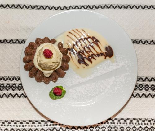 a plate with chocolate cookies and ice cream and a raspberry at Dacii Liberi Resort and Spa in Petrova