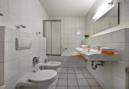 a white bathroom with a toilet and a sink at Hotel Katharinenhof in Werdau