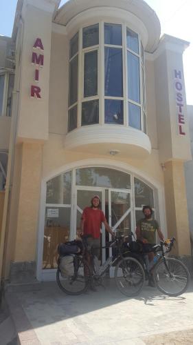 two men standing in front of a building with their bikes at Amir Hostel in Samarkand