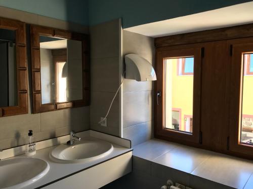 baño con 2 lavabos y ventana en Albergue Orion, en Castrojeriz