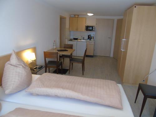 a bedroom with a bed and a kitchen with a table at Wein- Appartements Borth in Bretzfeld